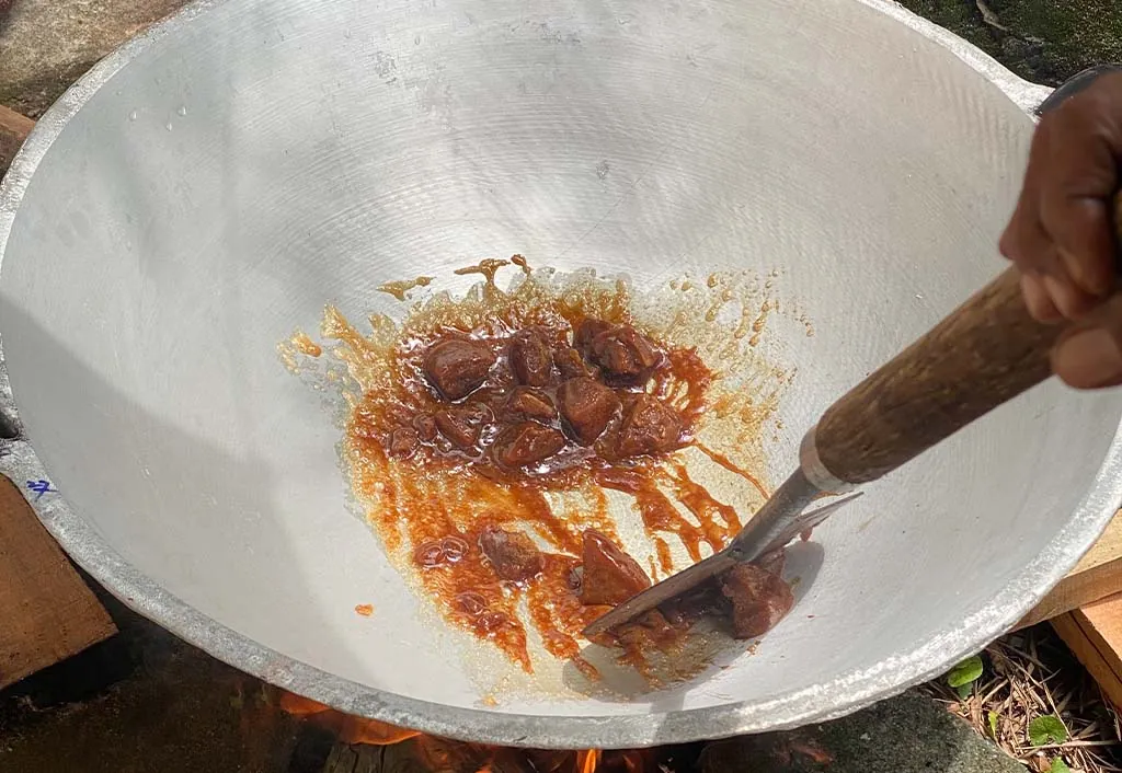 Dodol being stirred in a wide pan over a wood fire