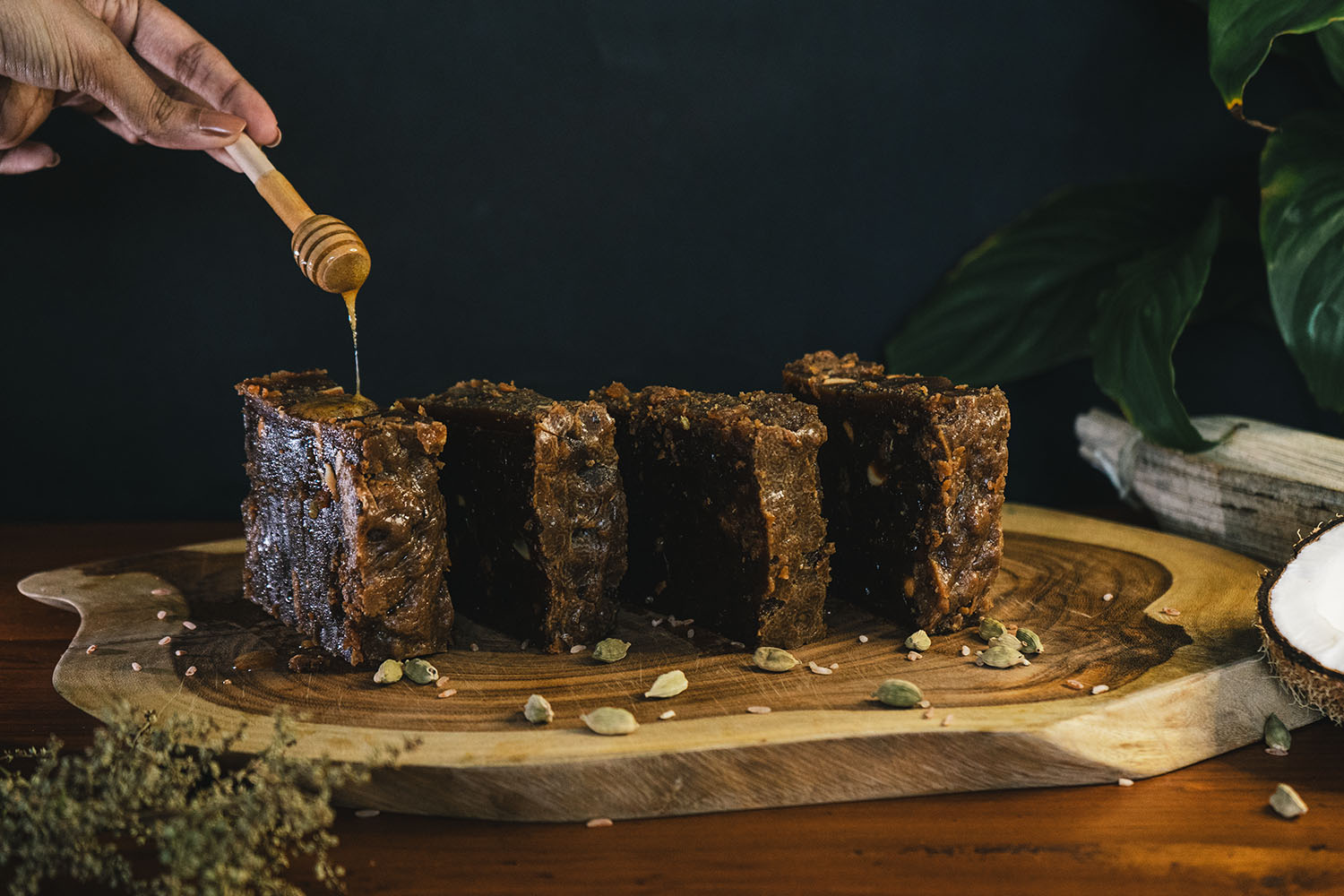 Slabs of kithul dodol on a teak board while honey is drizzled over them